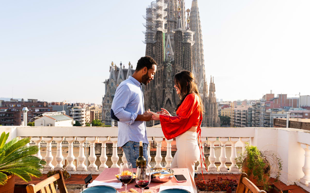 Couple sharing a romantic moment on a rooftop with Sagrada Família view