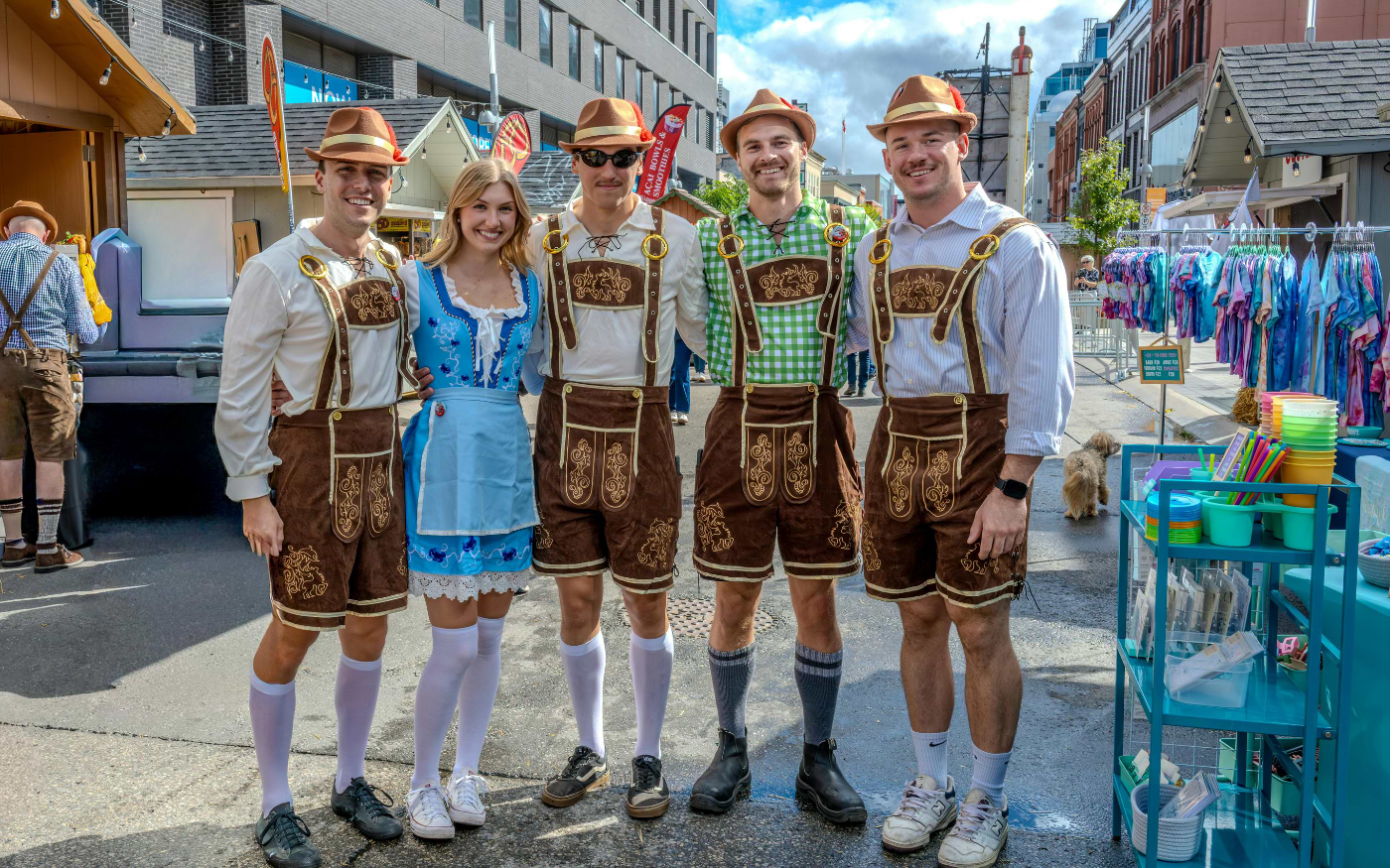 Group of five friends in traditional lederhosen and a dirndl at an Oktoberfest street festival