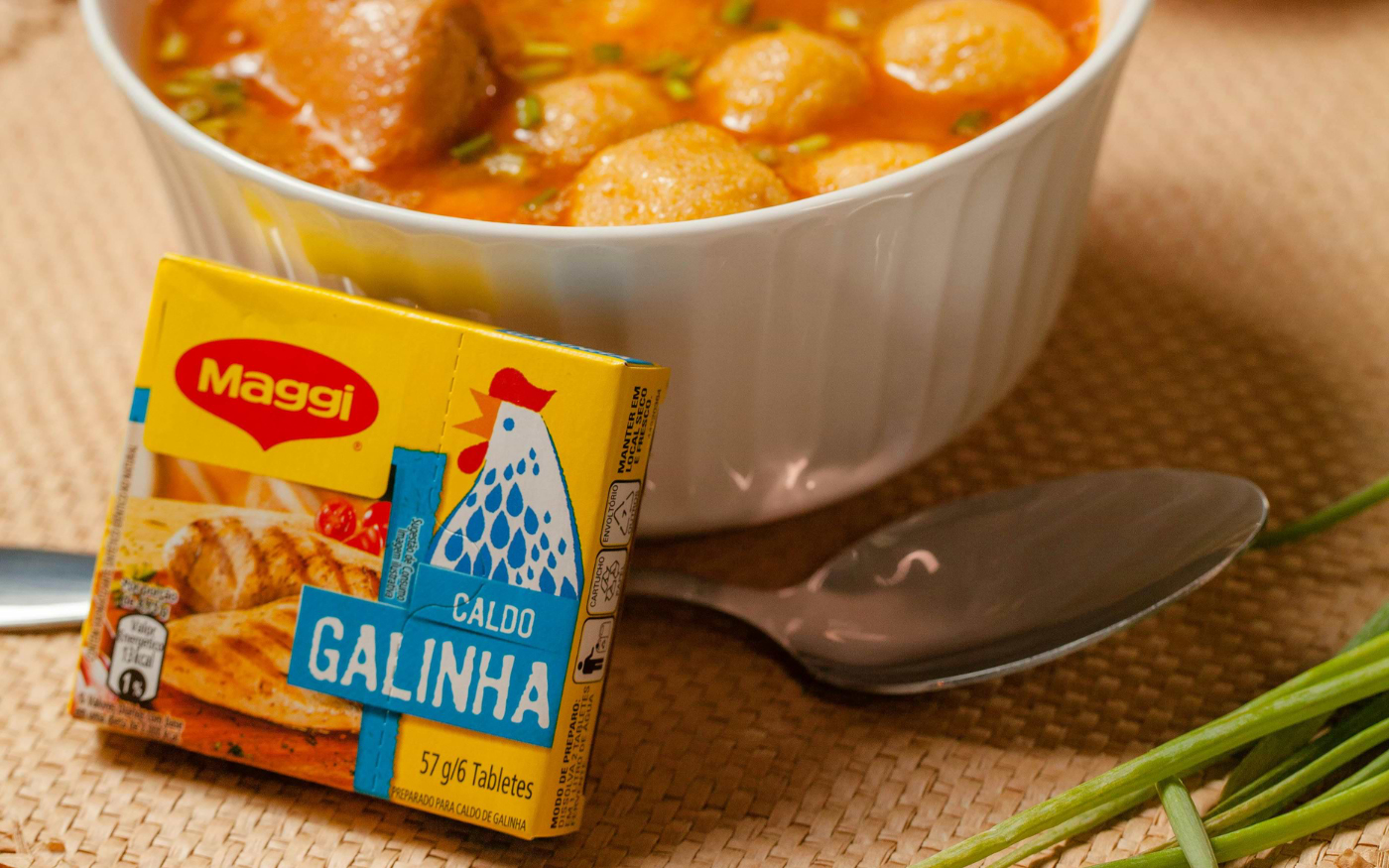 Maggi chicken bouillon cube box beside a bowl of soup with dumplings