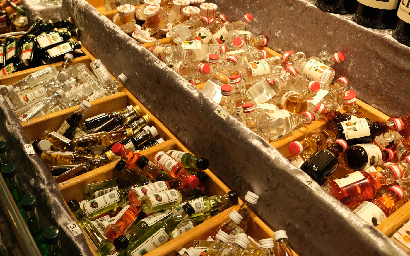 Wooden bins filled with miniature liqueur and schnapps bottles at a market stall