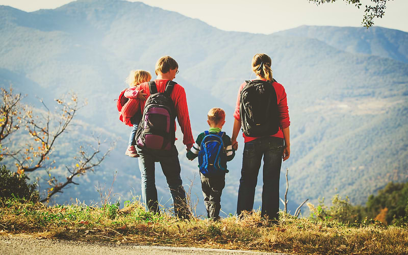Family with two children admiring a mountain view together, backpacks ready for a day hike near Zurich