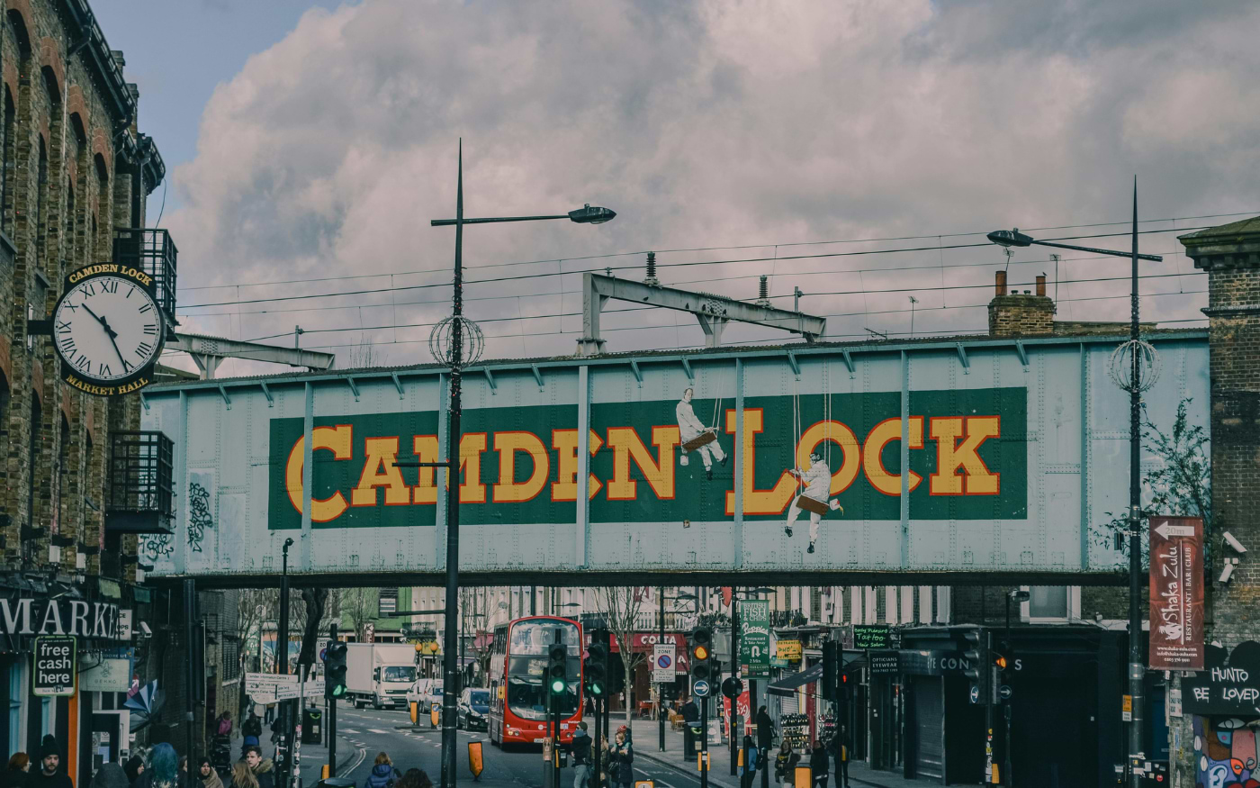 Camden Lock railway bridge sign and Camden Lock Market Hall clock, with a red double-decker bus on the street below
