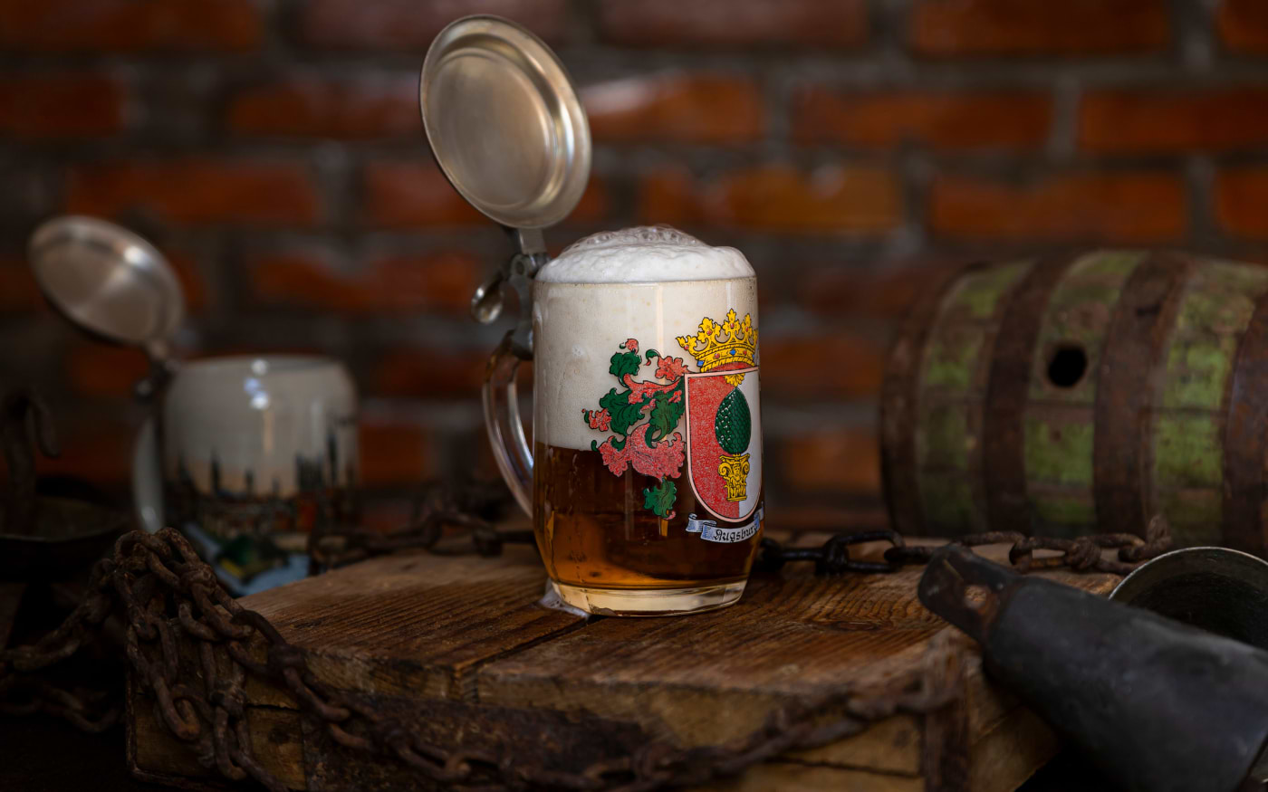 Bavarian beer stein with hinged pewter lid and Augsburg coat of arms on a wooden barrel with a rusty chain
