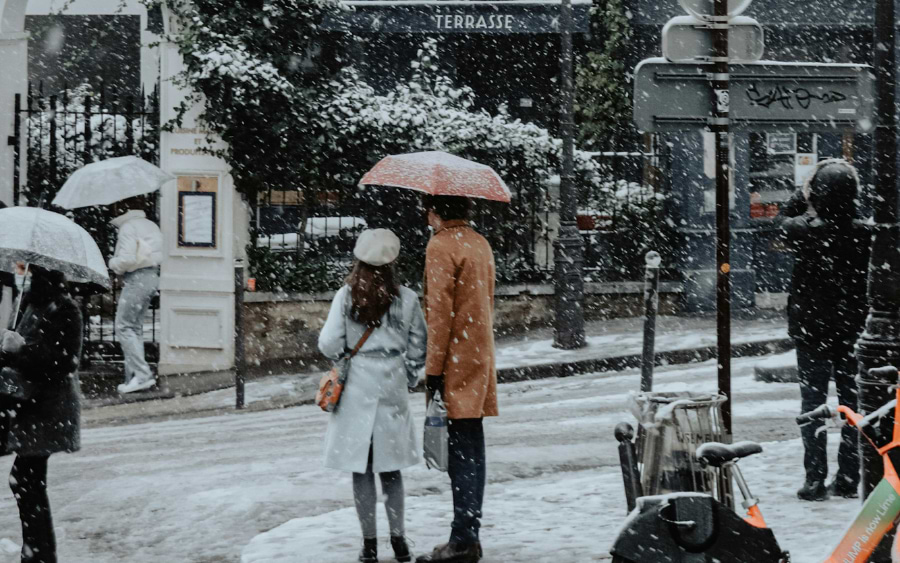 A couple walking hand-in-hand along the snow-dusted streets of Paris
