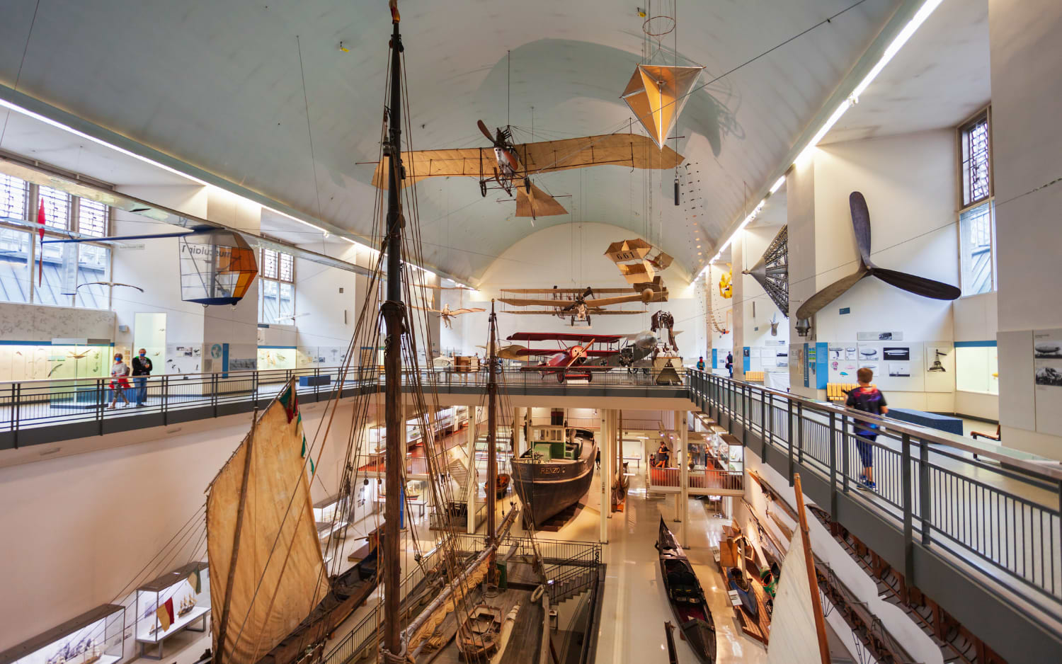 Deutsches Museum Munich: vintage biplanes, a glider and wooden sailing boats displayed across two floors of a bright, vaulted hall.