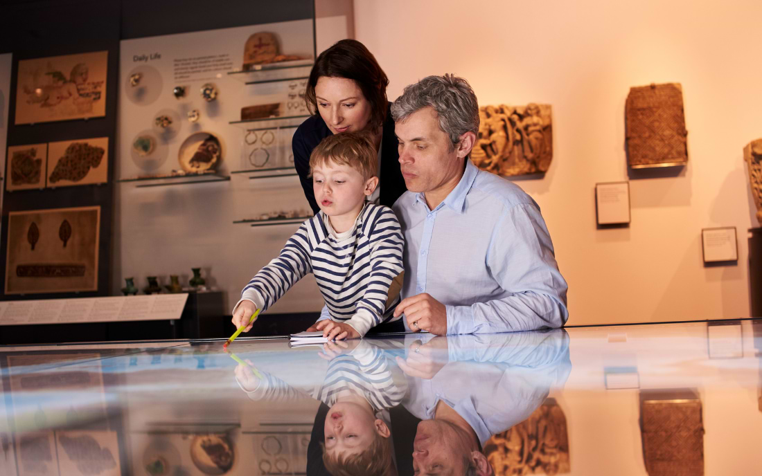 A family with a young child exploring an interactive exhibit at a history museum, Milan