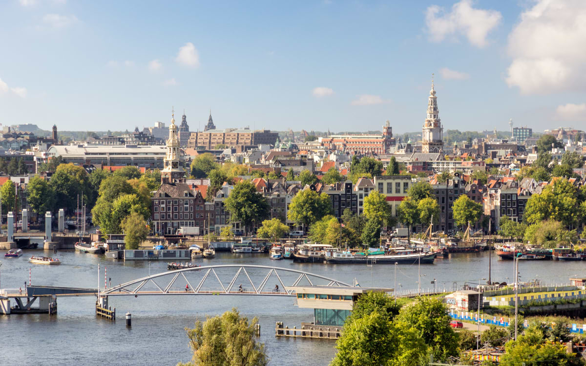 Luftblick auf Amsterdams Skyline mit Grachten, Kirchtürmen und Booten auf dem Fluss