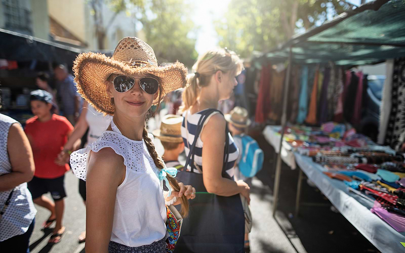 A woman browsing flea market stalls in Rome on a sunny day
