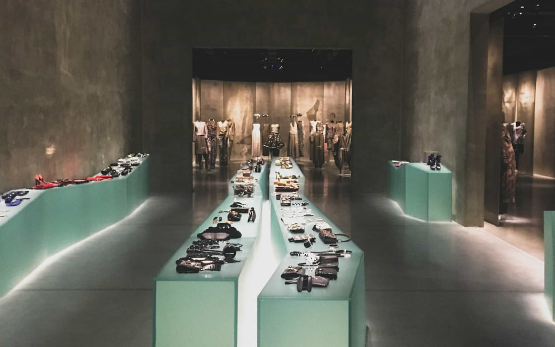 Interior of the Armani/Silos fashion museum in Milan, showing accessories displayed on mint-green plinths with mannequins in the background