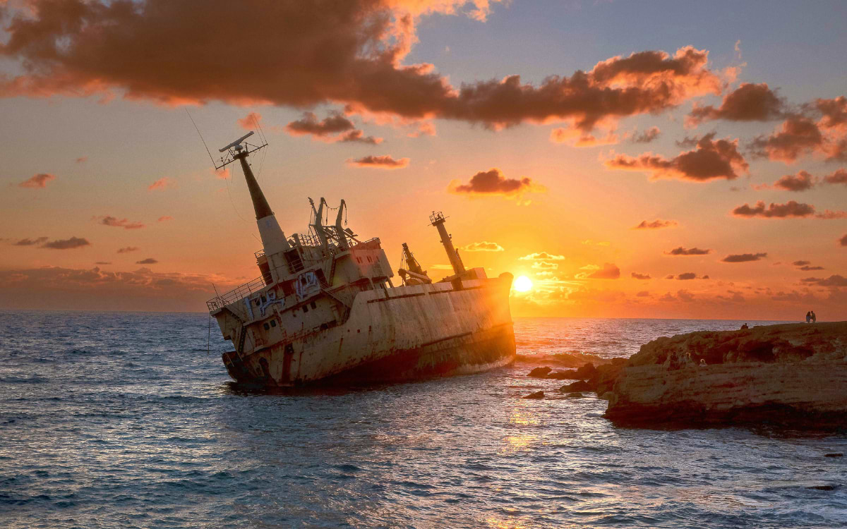 Rusty shipwreck tilted on rocks off the Paphos coastline at golden sunset, Cyprus