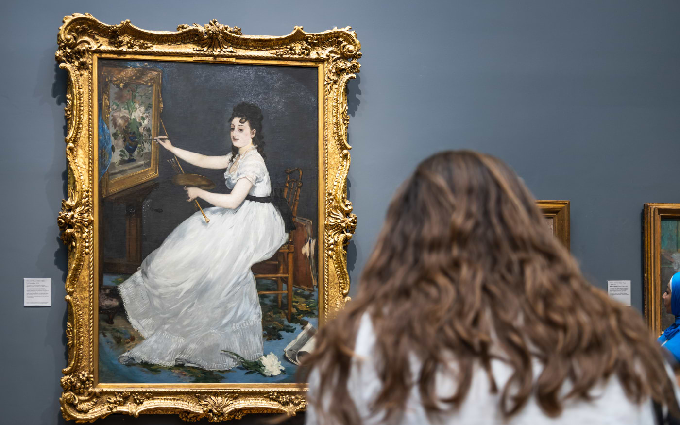 Visitor viewing Manetās portrait of Eva GonzalĆØs in an ornate gilded frame at the National Gallery in London