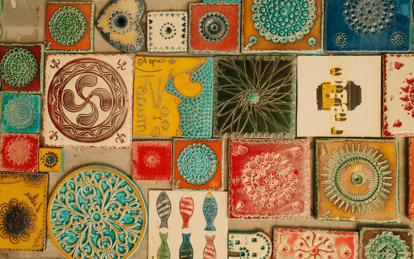 Colorful handmade ceramic tiles and azulejos with floral and fish patterns at a Portuguese souvenir market stall.