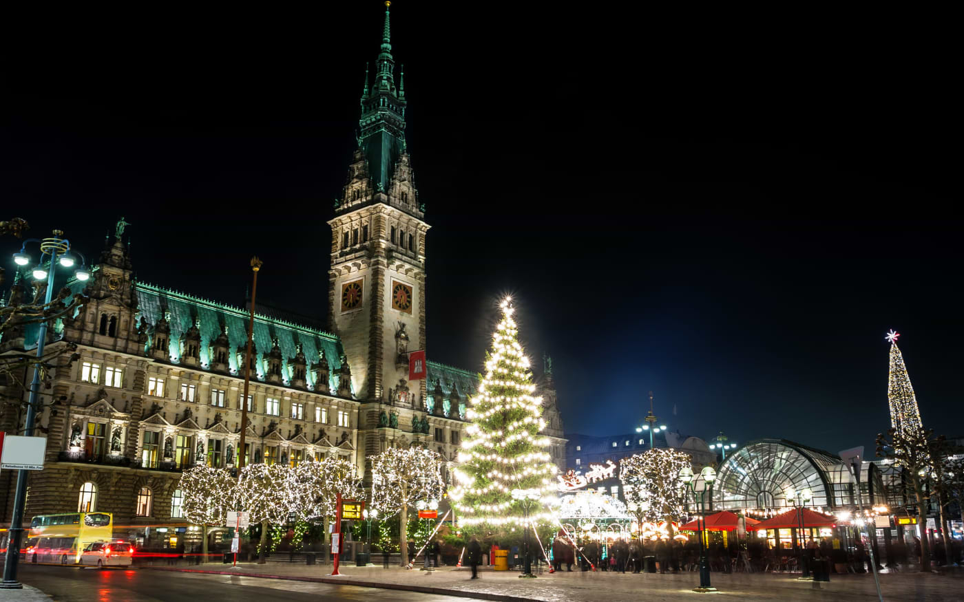 Beleuchteter Torbogen des Hamburger Weihnachtsmarkts mit Weihnachtsmann und Rentieren vor dem Hamburger Rathaus bei Nacht