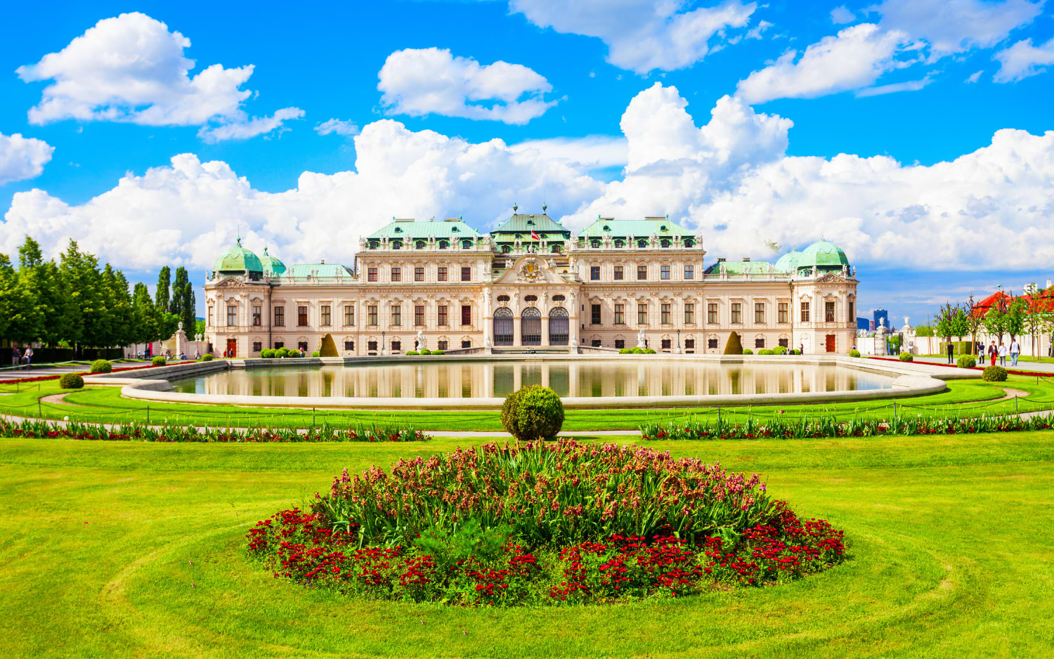 Upper Belvedere in Vienna, Baroque palace with green roofs reflected in a pond, with a red flowerbed on the lawn
