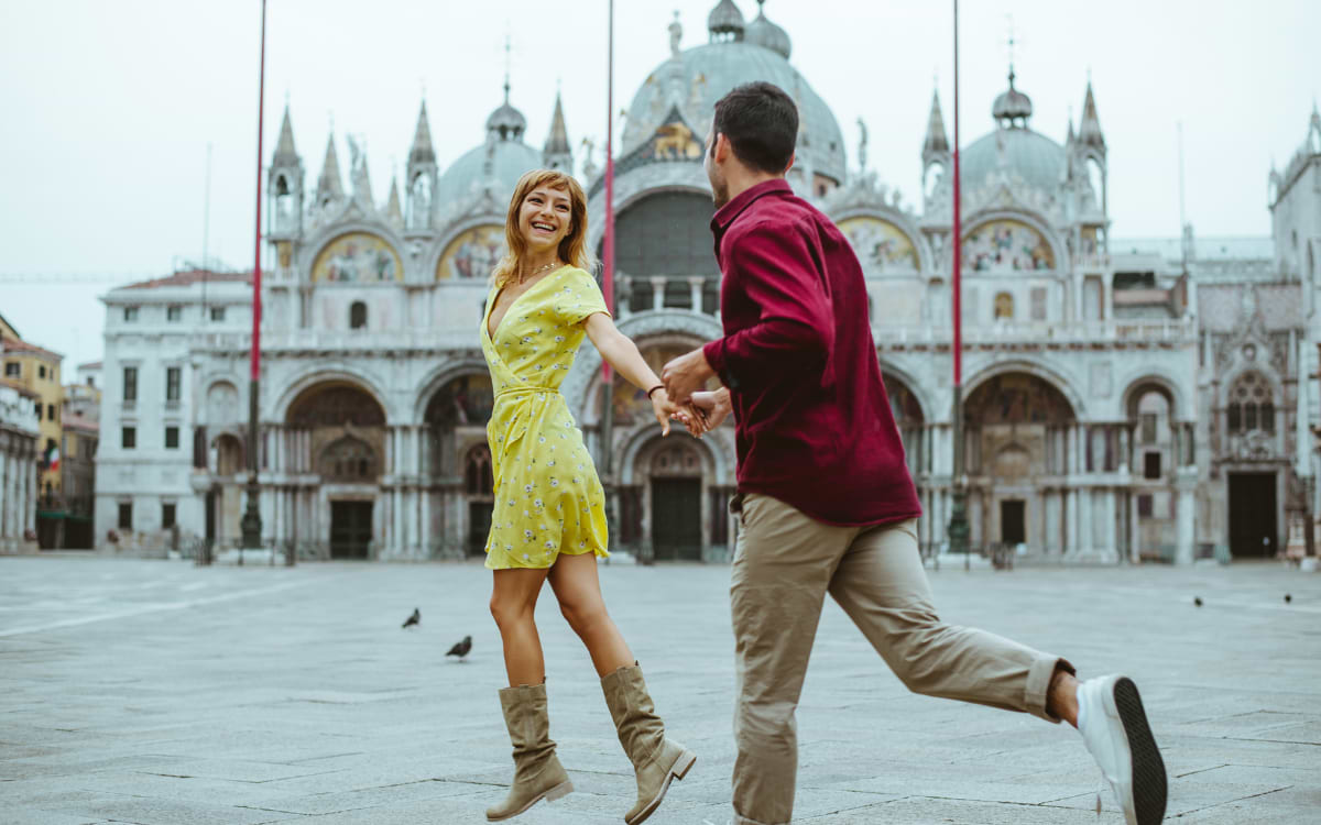 Happy couple dancing and holding hands in Piazza San Marco, Venice