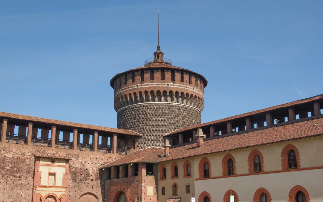 The circular Torre del Carmine tower of the Castello Sforzesco in Milan against a clear blue sky