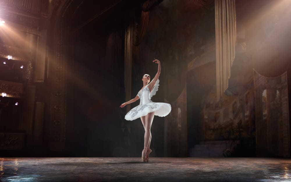 An audience watching a graceful ballet performance on the illuminated stage