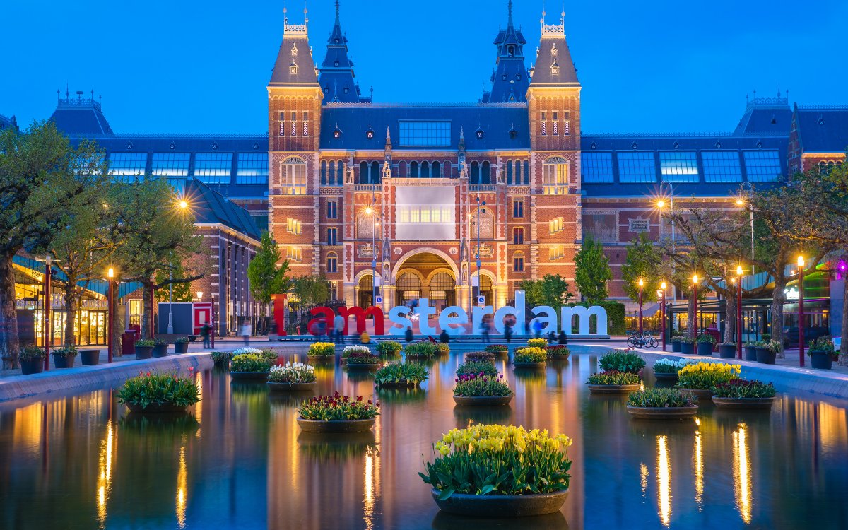 Rijksmuseum bei Nacht mit I amsterdam Schriftzug und Spiegelbecken im Museumviertel