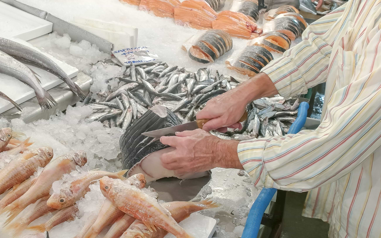Fishmonger filleting fresh catch on an icy counter at the Varvakeios Agora central market in Athens