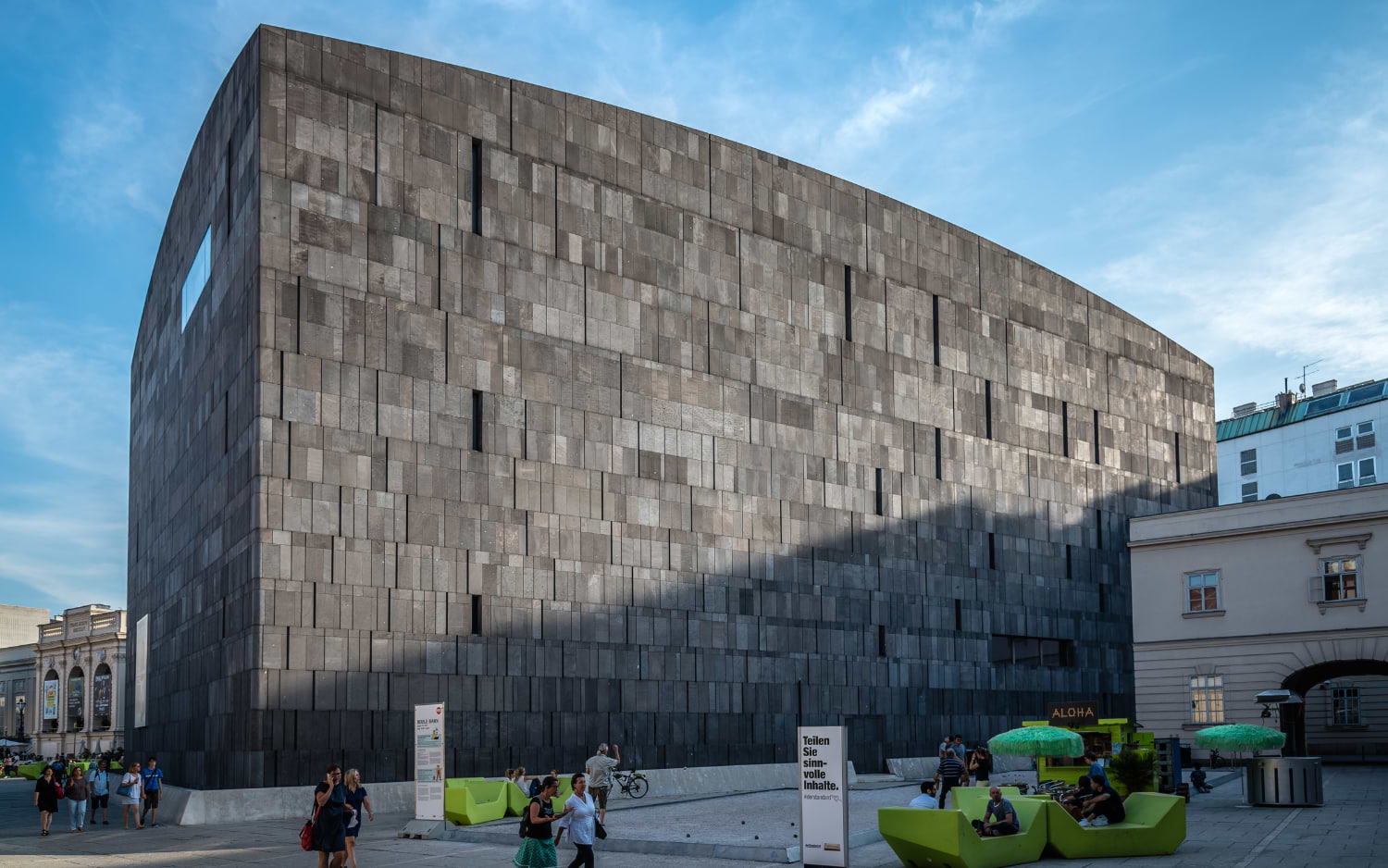 mumok Vienna, the dark basalt cube in the MuseumsQuartier courtyard, with visitors on bright green lounge seats