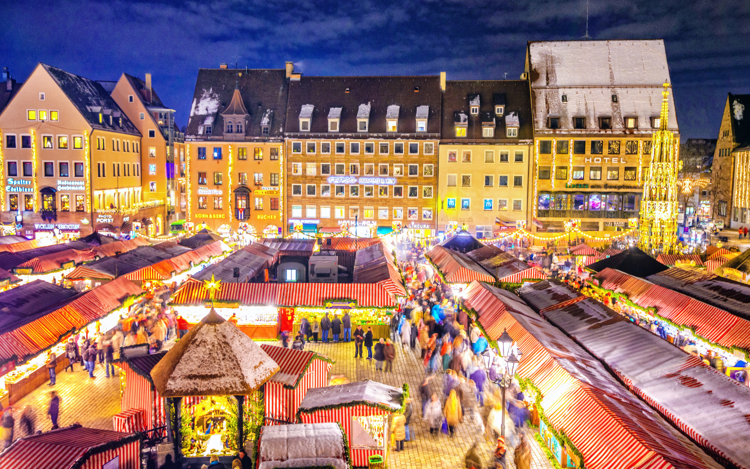 Nuremberg Christkindlesmarkt on the Hauptmarkt with red-and-white striped stalls, crowds and the Schƶner Brunnen