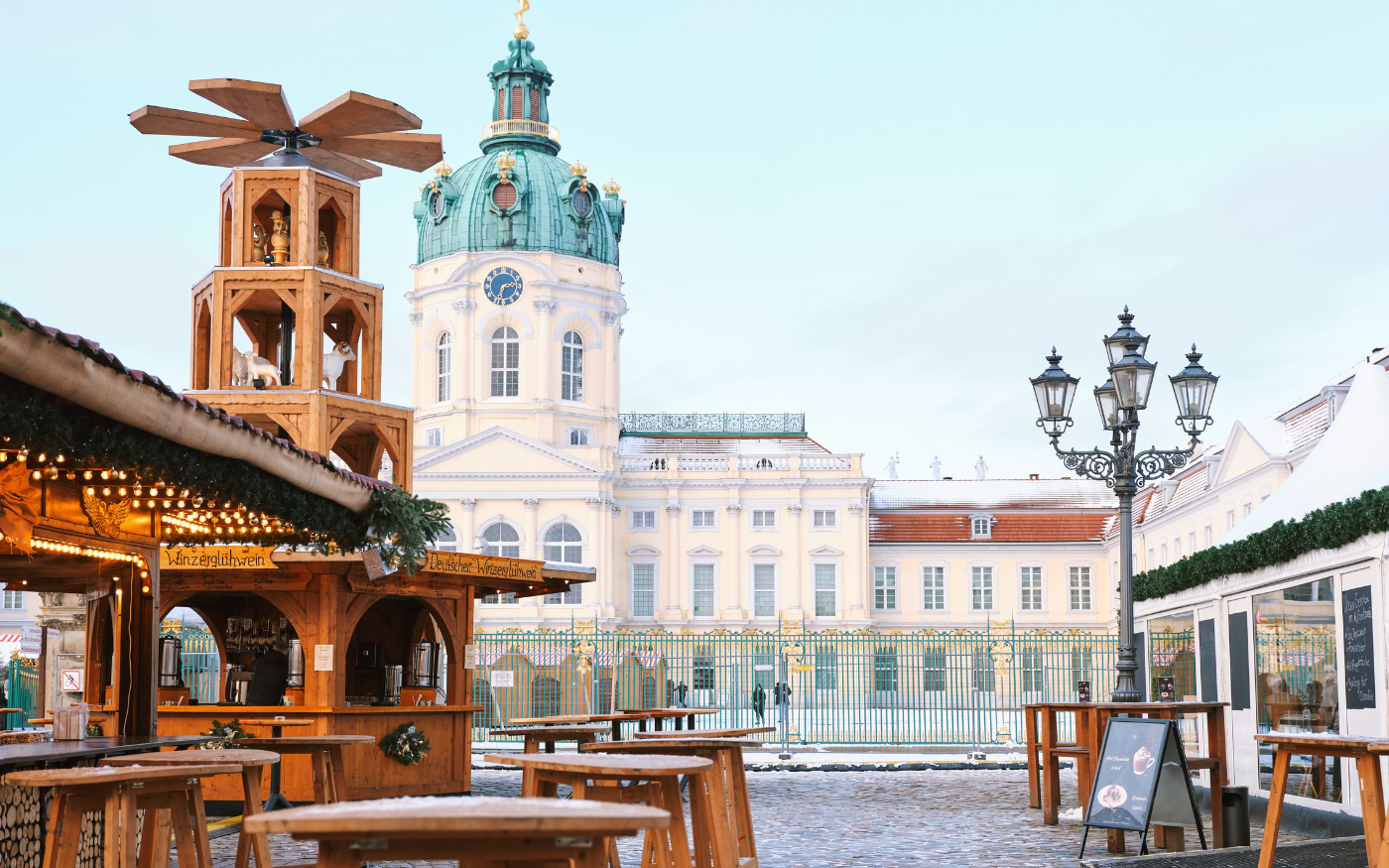Christmas pyramid and mulled wine huts in front of snowy Charlottenburg Palace at the Berlin Christmas market