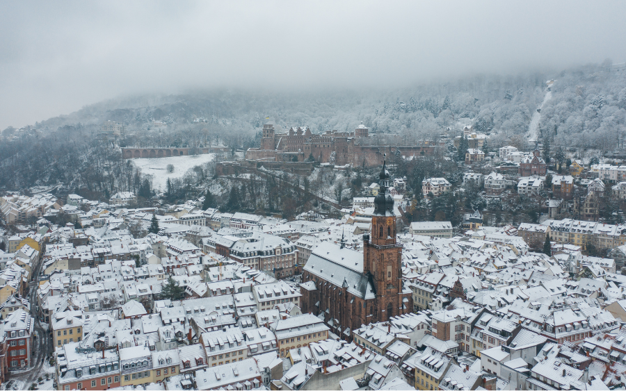 The historic Heidelberg Castle overlooking the Neckar River, with the cityscape blanketed in snow