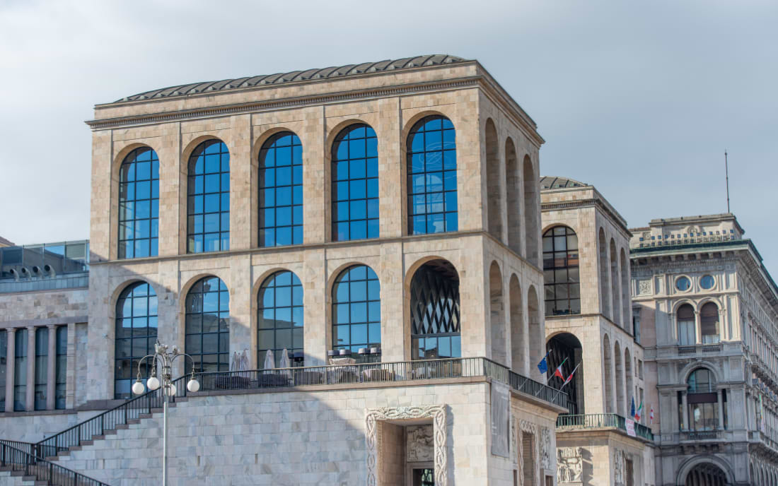 The modern stone facade of the Museo del Novecento in Milan, featuring large arched windows 