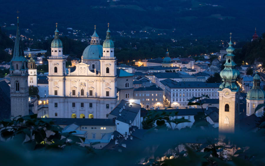 The baroque architecture of Salzburg's Old Town blanketed in snow under a clear winter sky.