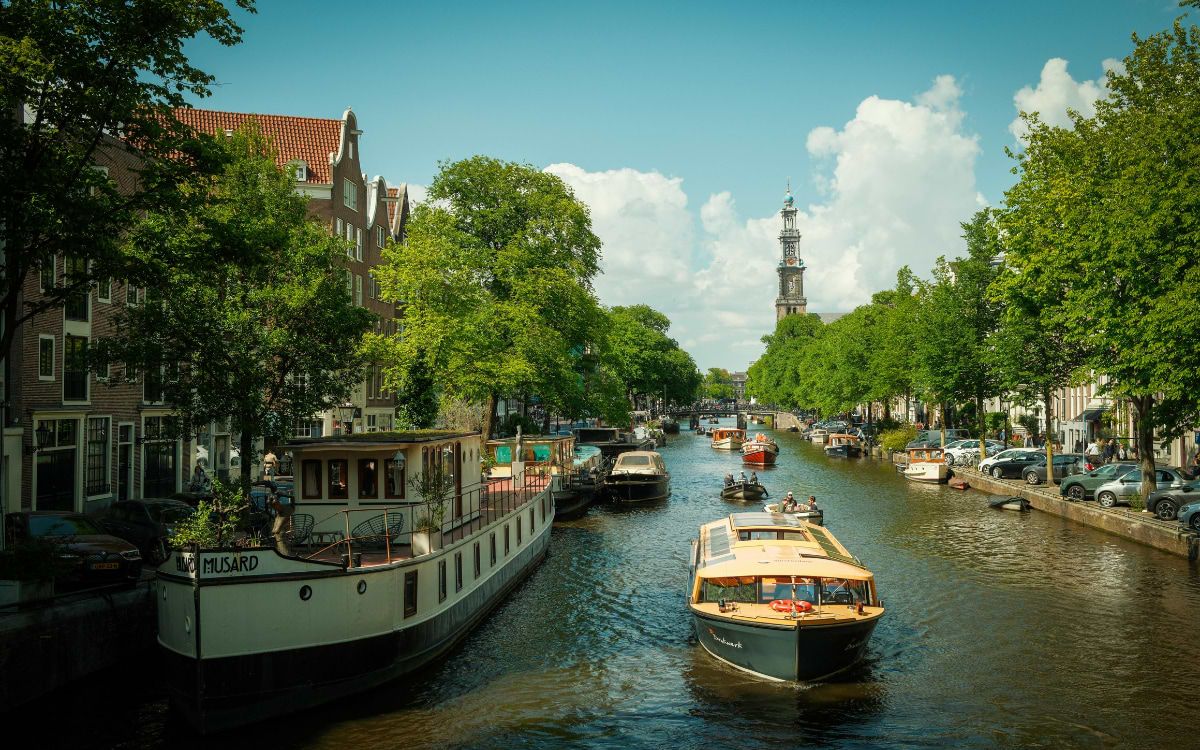 Canal cruise boat on a Amsterdam waterway with the Westerkerk tower in the background