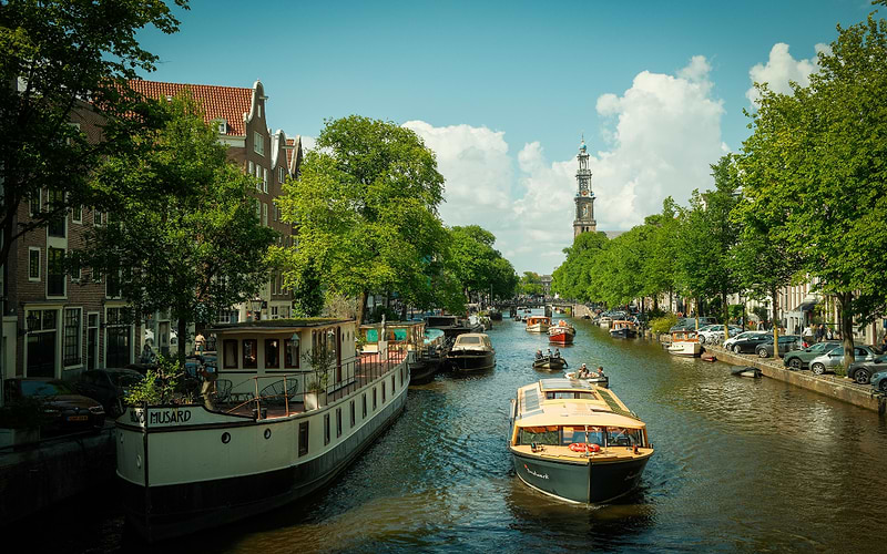 Canal cruise boat on a Amsterdam waterway with the Westerkerk tower in the background