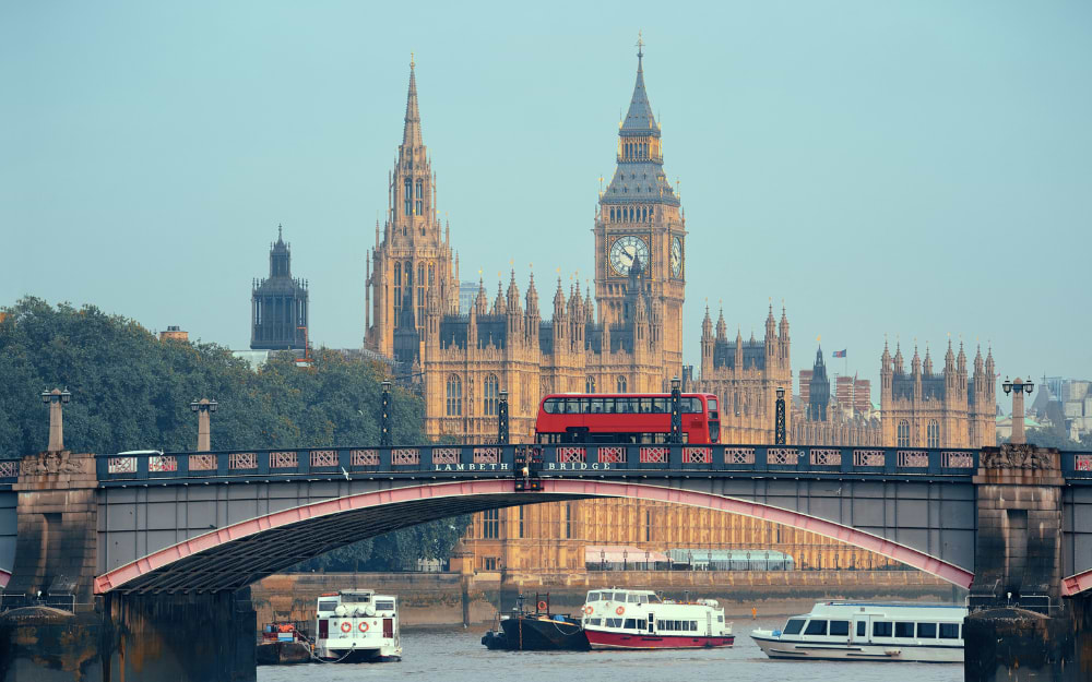 Red double-decker bus on Lambeth Bridge with Big Ben and Houses of Parliament, London