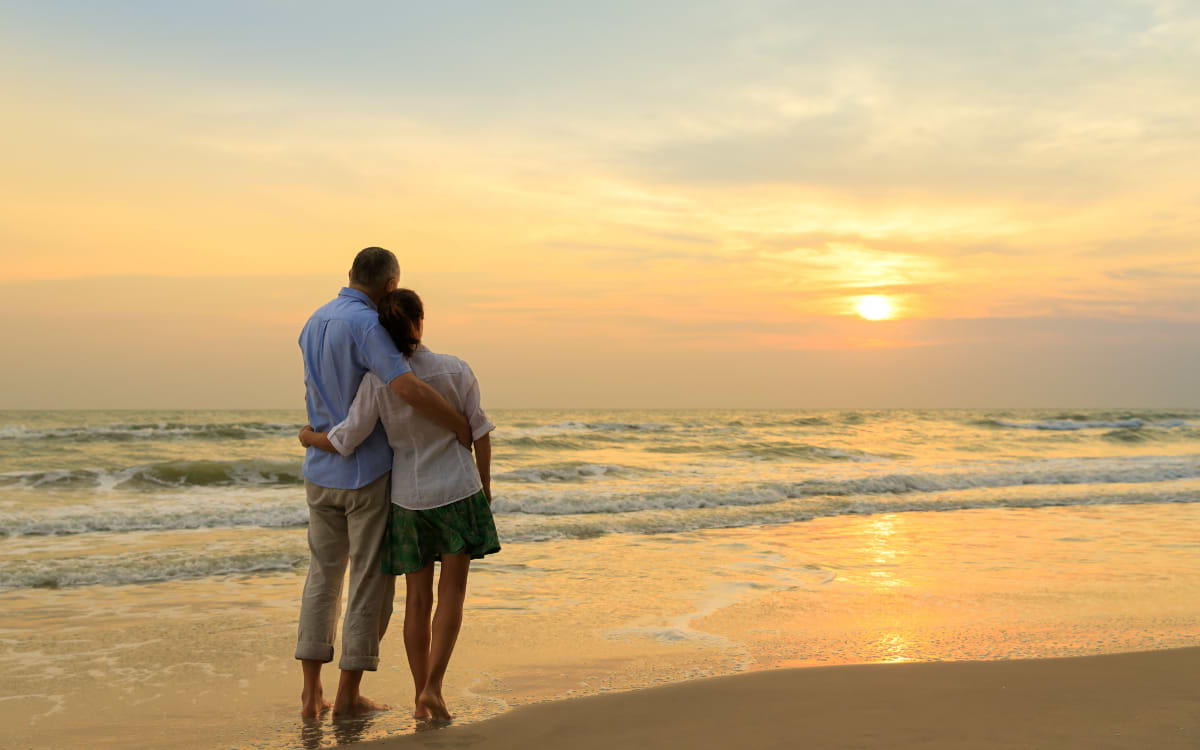 Couple embracing on a sandy beach watching a golden sunset together in Paphos