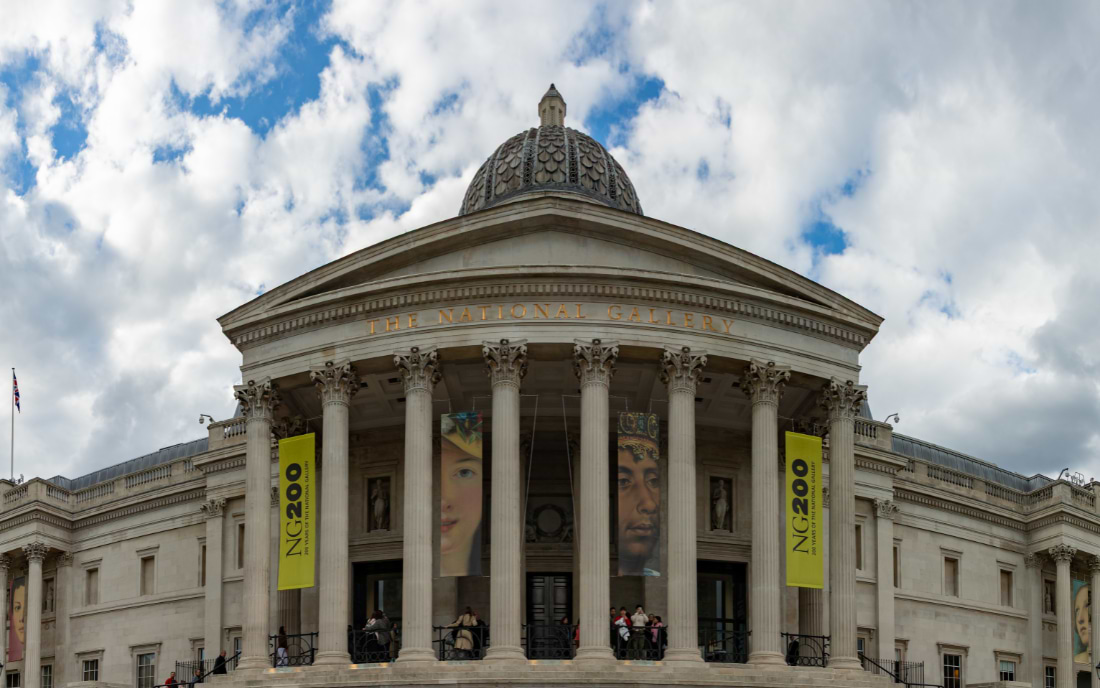 The neoclassical facade of the National Gallery on Trafalgar Square in London, decorated with yellow NG200 anniversary banners