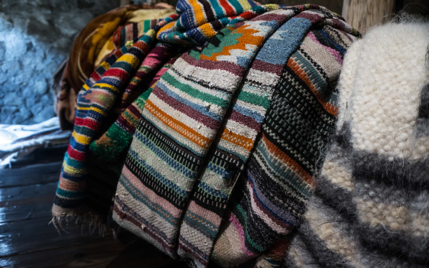 Stack of traditional Portuguese wool blankets and rugs in colorful striped patterns, handwoven regional textiles.