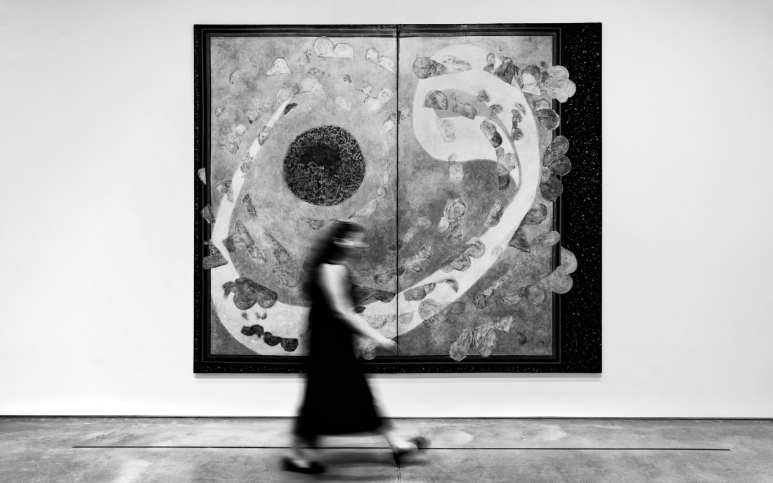 A blurred figure of a woman walking past a large abstract painting in a contemporary art gallery, Athens