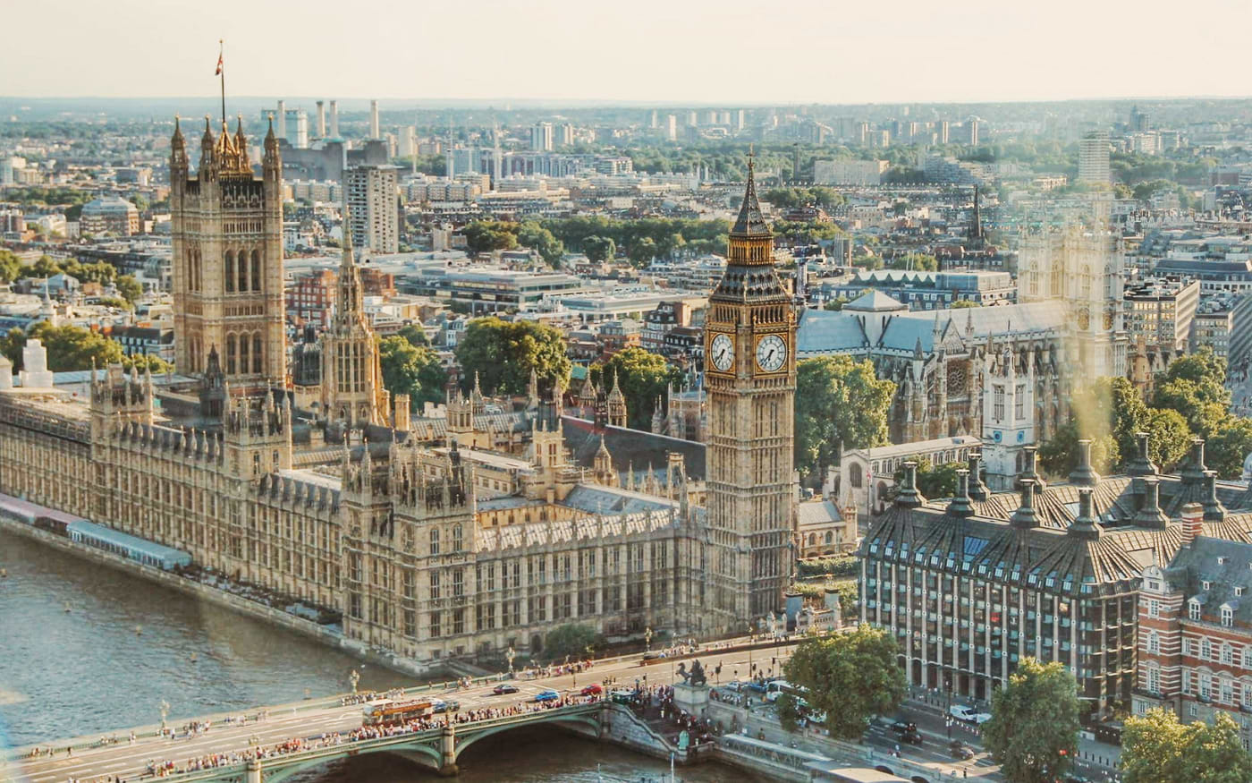 Aerial view of the Houses of Parliament, Big Ben and Westminster Abbey, with crowds and a bus crossing Westminster Bridge