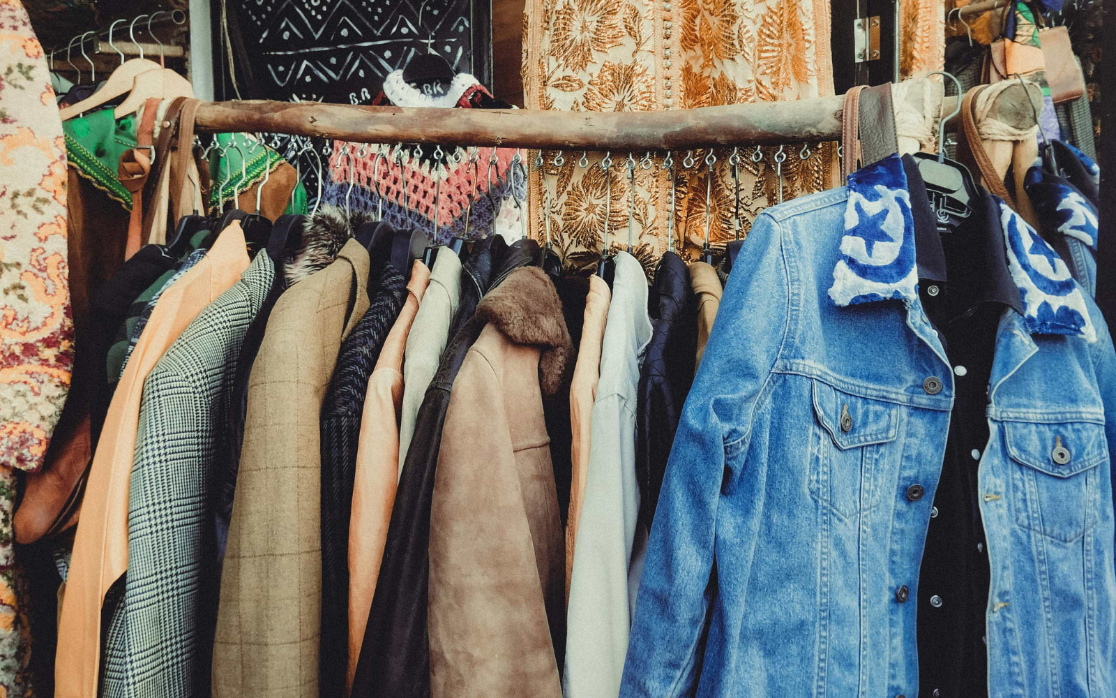 Rack of vintage coats, tweed jacRack of vintage coats, tweed jackets and patched denim jackets at an outdoor flea market stallkets and patched denim jackets at an outdoor flea market stall