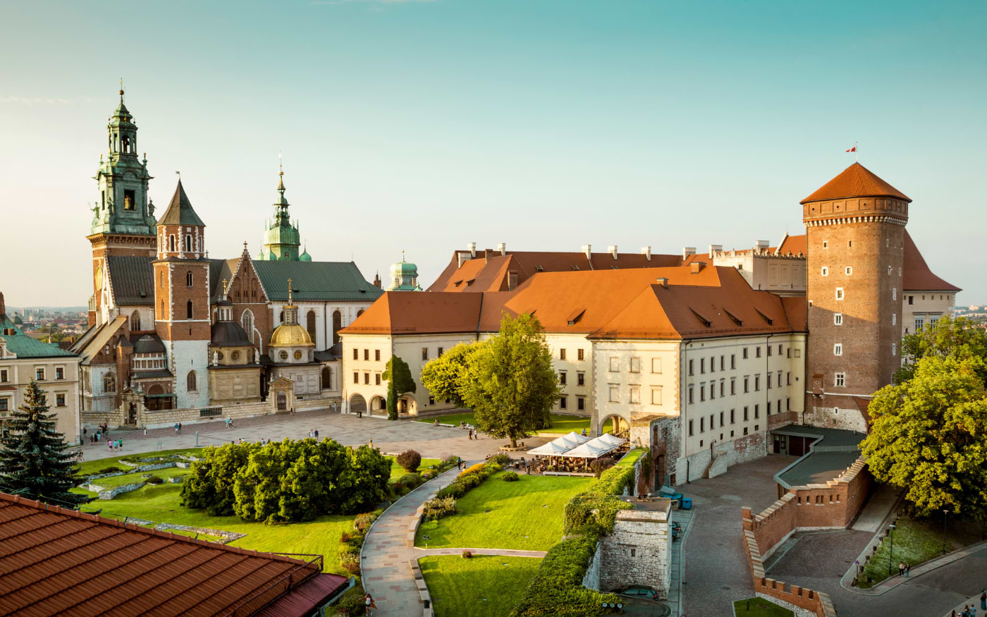 Wawel Royal Castle and Wawel Cathedral in Krakow with green domes, a golden chapel dome and orange roofs in warm light