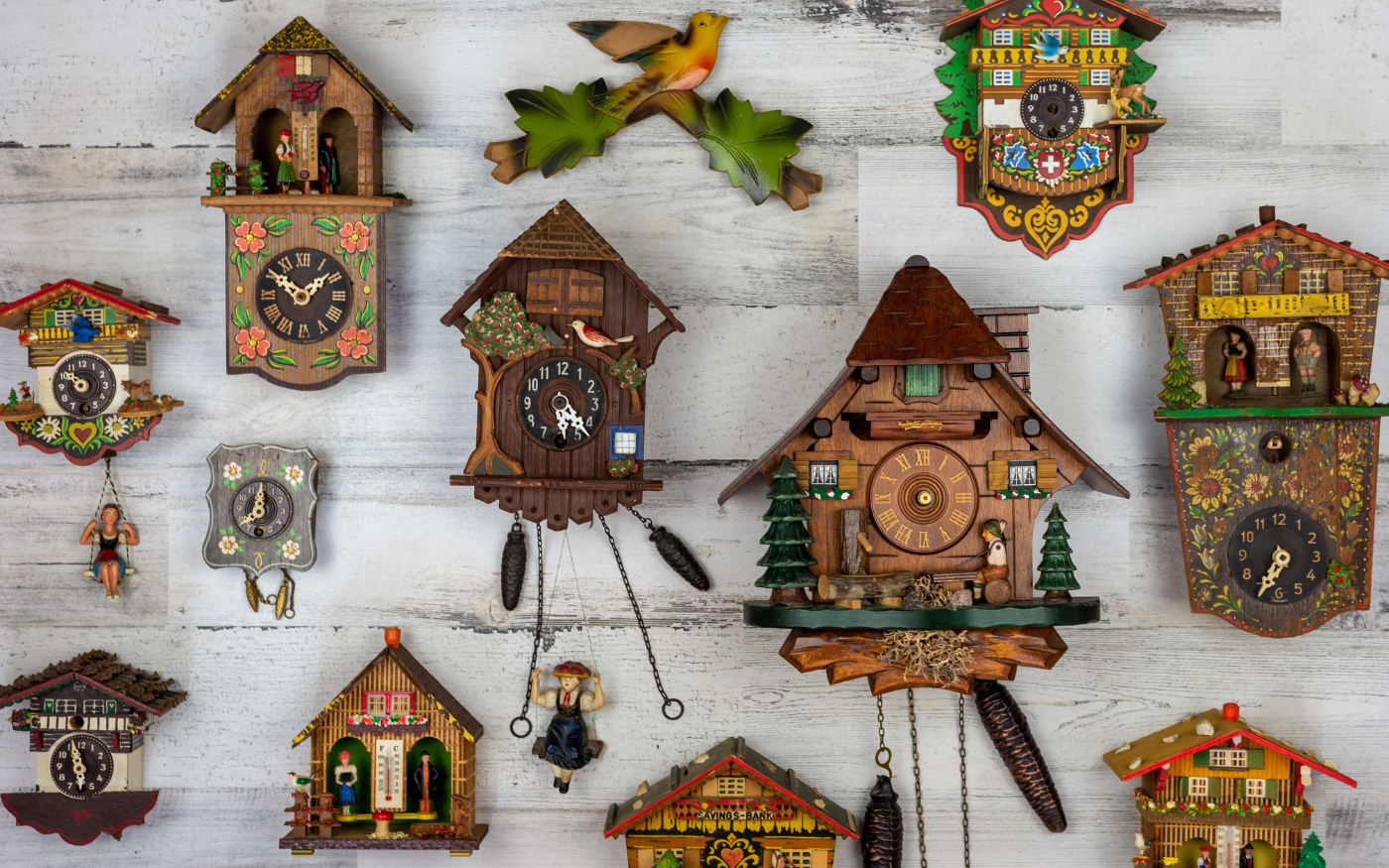 Collection of Black Forest cuckoo clocks with carved wooden houses on a white wall
