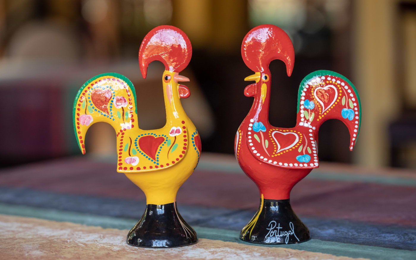 Two hand-painted ceramic Barcelos roosters, the iconic symbol of Portugal, displayed as colorful souvenirs.