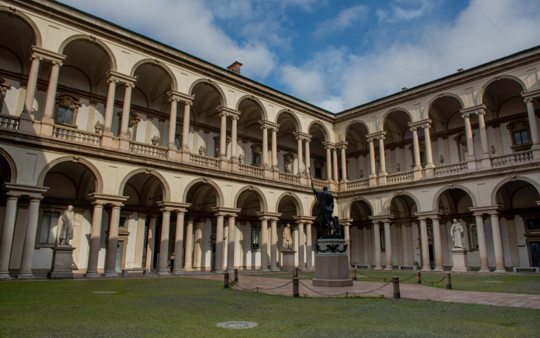 The elegant two-storey arcaded courtyard of the Pinacoteca di Brera in Milan, with a central bronze statue on the lawn