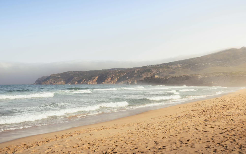 Sandy beach at Costa da Caparica with Atlantic Ocean waves, Lisbon, Portugal.