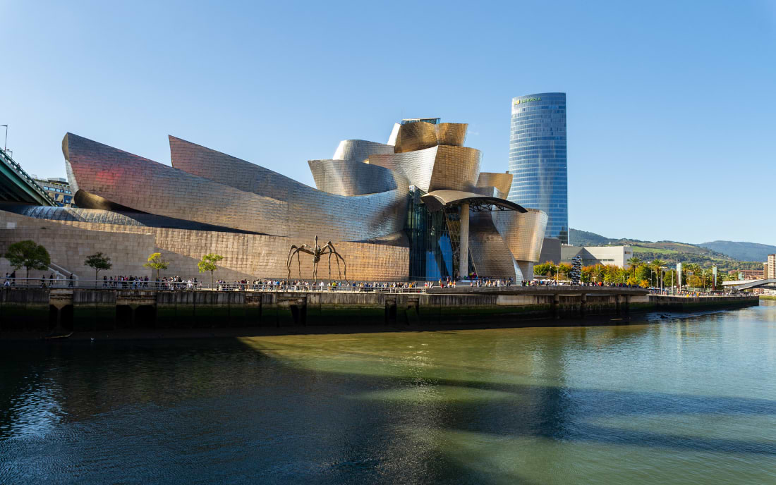 Guggenheim Museum Bilbao with titanium-clad facade and Maman spider sculpture on the banks of the Nervión River