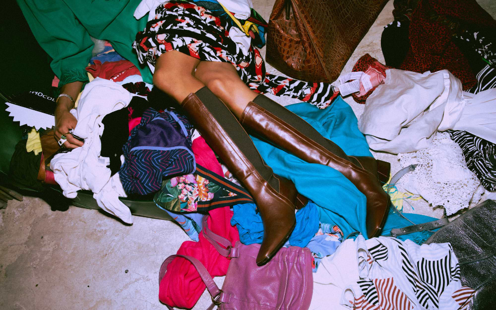 Colourful pile of second-hand clothing and vintage accessories spread across the floor at an Amsterdam flea market