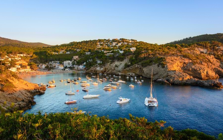 Sunset view at a beach in Ibiza with boats and people enjoying the scenery